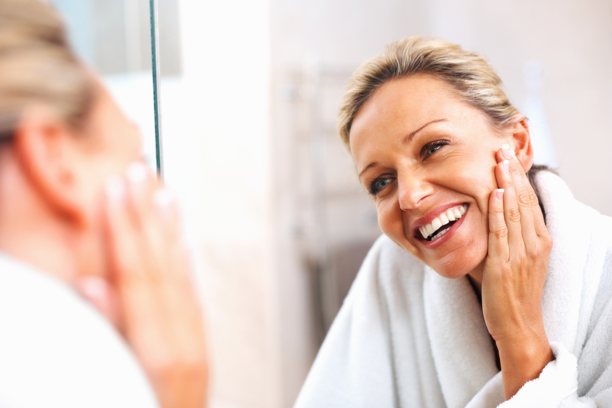 woman smiling in the mirror after learning about what signals the end of menopause